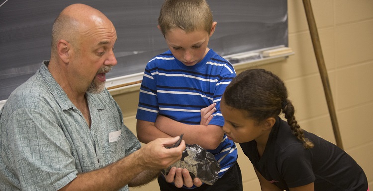 Dr. Phil Carr, Chief Calvin McGhee Endowed Professor of Native American Studies, gives a hands-on archaeology lesson to Kolby Rayborn and Kylee Langham during Art and Archaeology Day.