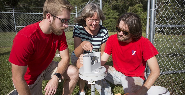 Meteorology majors Daniel Martin, left, and Mark D. Smith, right, assist Dr. Sytske Kimball, chair of earth sciences and professor of meteorology, with the USA Mesonet station on USA's main campus. Martin and Smith are both mesonet technicians.