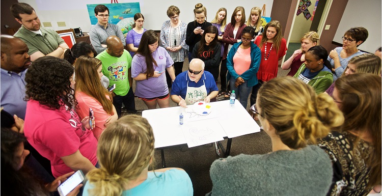 Each year, South graduate and artist Ricky Trione visits classes in the College of Education. A lesson quickly emerges: If a blind man can create boldly colored, vibrant paintings, and sit on the floor of a classroom teaching kindergarteners how to do the same, then teachers can use art to communicate with almost anyone. data-lightbox='featured'