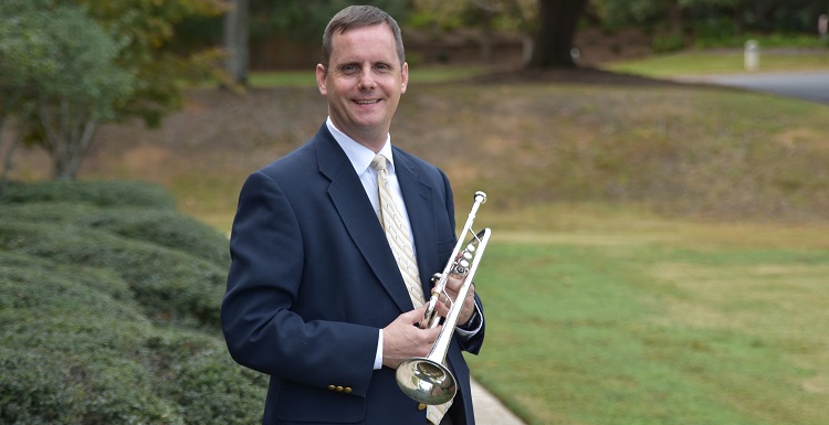 Dr. Peter Wood standing on lawn with trumpet