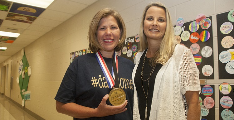 Newly-named Alabama Teacher of the Year Chasity Collier, left, receives a special 50th Anniversary medallion from Dr. Andrea Kent, dean of the University of South Alabama College of Education, during a surprise celebration pep rally at Dawes Intermediate School. Earlier this year, South Alabama’s College of Education celebrated 50 years. Collier teaches fifth-grade science at Dawes Intermediate School.