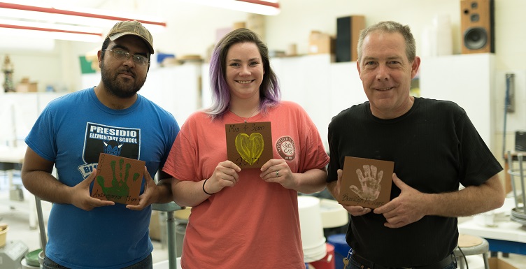 Graduate student Ramon Deanda, left, junior Lauren Carroll and Professor Tony Wright show some of the hand-print tiles that will be on display at Medal of Honor Park's playground.