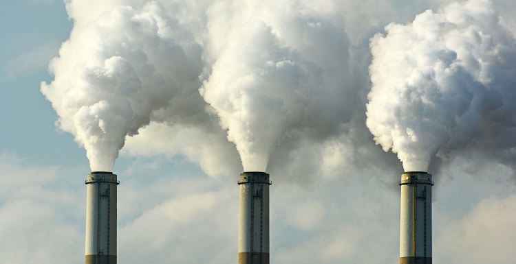 three smoke stacks with smoke billowing out