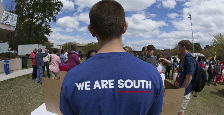 boy standing with back to camera wearing t-shirt bearing the "We Are South" branding logo