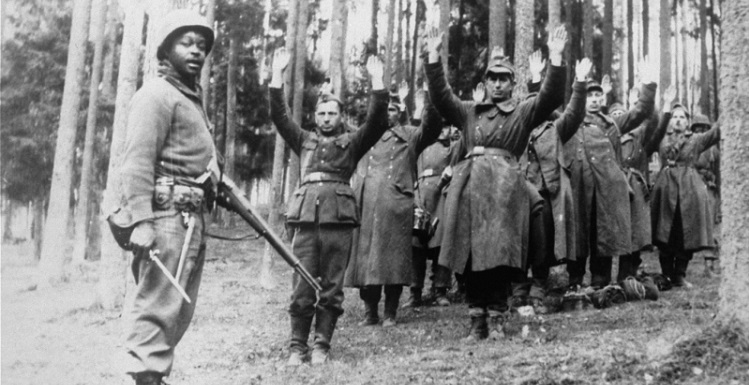 An African-American soldier with the 12th Armored Division, Seventh U.S. Army, stands guard over a group of captured German soldiers. Photo courtesy of the United States Holocaust Memorial Museum.