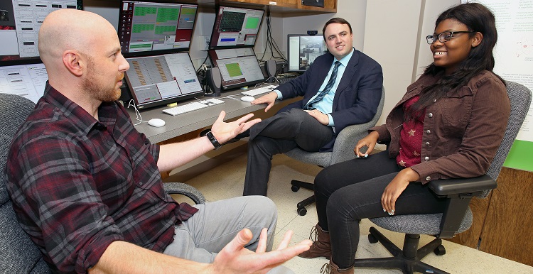 USA physics majors Paul White, left, and Erriel Milliner, right, discuss the NOvA research project with Dr. Martin Frank, assistant professor of physics, in the lab where they interact with other researchers around the country.