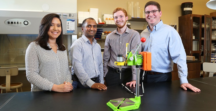 Dr. Dhananjay Tambe, second from left, an assistant professor in mechanical engineering and pharmacology, worked with engineering students, from left, Cassandra Chapman, Brandon Stokley and Quentin Morris to develop the "Tighten It" smart drill prototype. Chapman and Stokely graduated Saturday. 