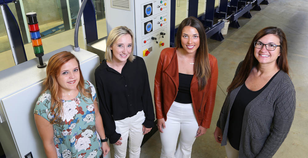 University of South Alabama engineering students Brittany McMillan, Peyton Posey and Evan Mazur are researching storm surge impacts on barrier islands with Dr. Stephanie Smallegan,  assistant professor of civil, coastal and environmental engineering. Behind them is the College of Engineering's wave flume, which can be filled with water and manipulated to simulate various wave actions found in landfalling hurricanes.
