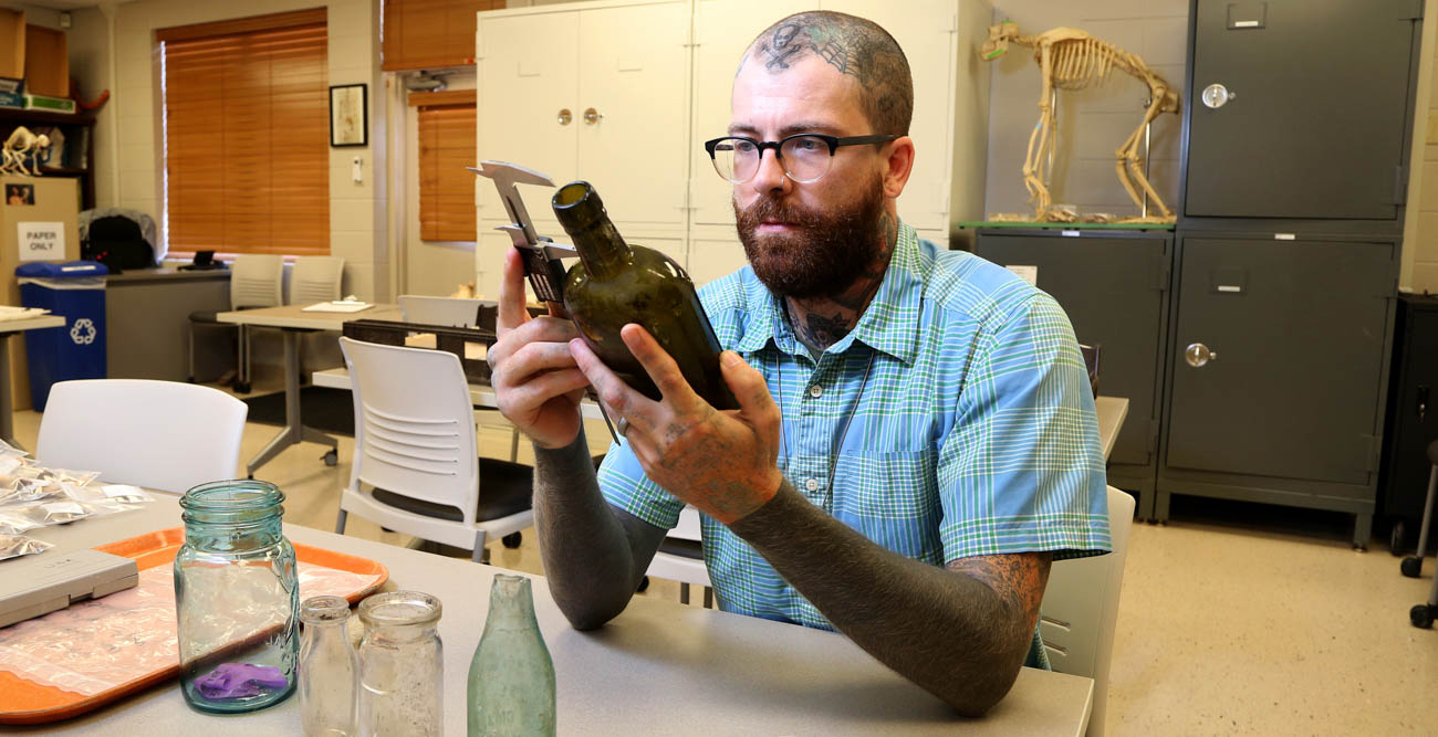 Dusty Norris, a graduate of the University of South Alabama’s anthropology program, is using an archaeology tool to record information about one of the artifacts found at the sites of the shotgun houses in areas of downtown Mobile. This preliminary work is being done as plans for the Mobile River Bridge and Bayway project moves forward.