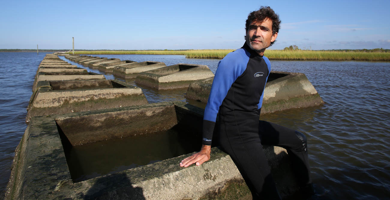 Dr. Just Cebrian, a marine science professor at the University of South Alabama, sits atop a mile-long row of concrete blocks placed between Portersville Bay and Little Bay to defend against erosion. The project was initiated after a berm was destroyed by Hurricane Katrina in 2006. The result: Sea grass that was planted has flourished, offering protection against hurricanes and for seafood and wildlife habitats. 