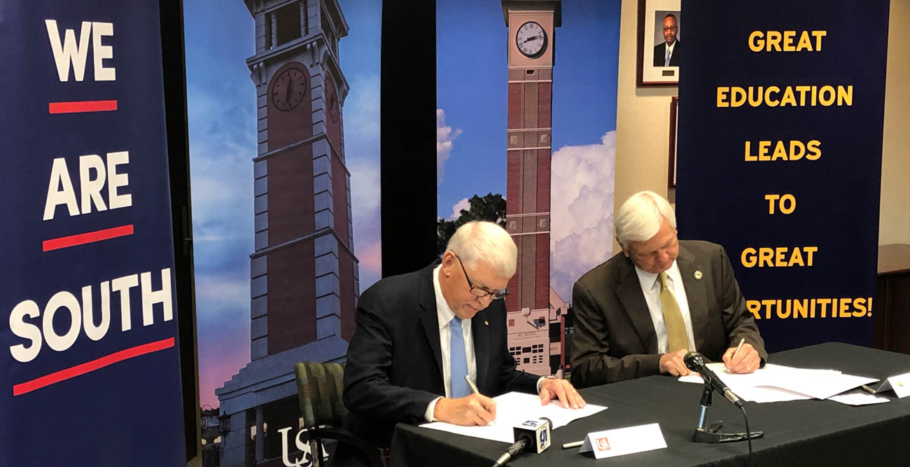 University of South Alabama President Tony Waldrop, left, and Pensacola State College President Edward Meadows sign documents officially joining the two institutions as part of South's "Pathway USA" program that streamlines the transition to USA for transfer students who earn their associate’s degree from Pensacola State.  