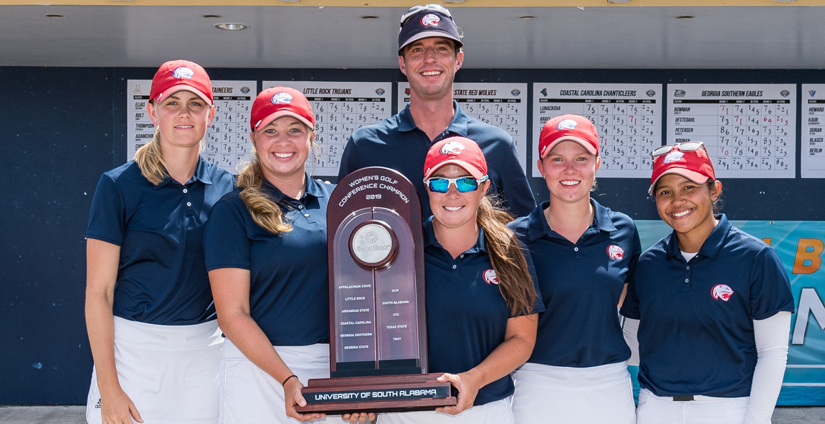 The women's golf team – from left, Caroline Berge, Lexi Worrell, MacKenzie Peyton, Julie Hovland and Siti Shaari, with Coach Matt Luther – claimed the Sun Belt Conference championship when it finished with a season-low 877 combined score at the LPGA International – Hills Course.