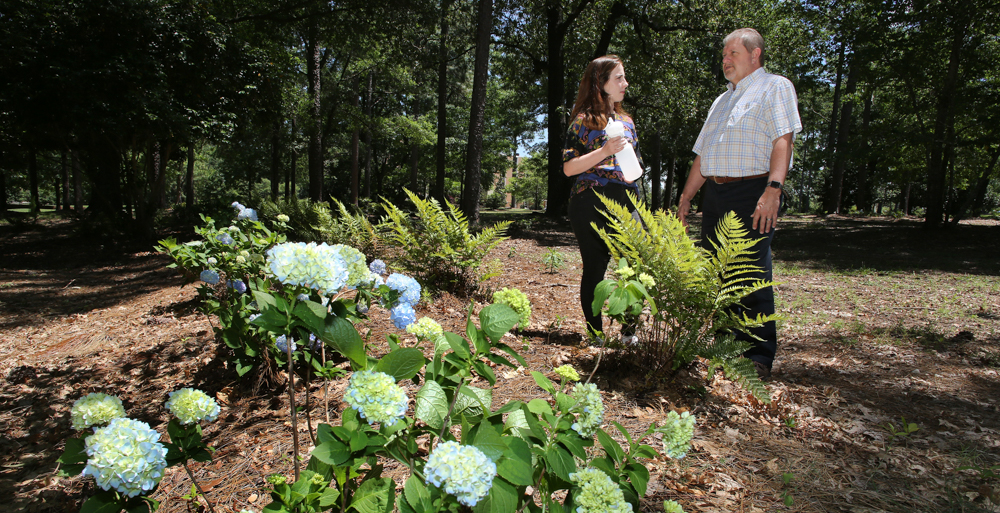 Dr. Kevin White, professor and chair of the department of civil, coastal and environmental engineering, and Jordan Blackmon, sophomore civil engineering major, stand on the edge of one of  five landscaped bioinfiltration swales near Meisler Hall. The swales help capture storm water runoff instead of it running off on the surface and eroding soil that eventually deposits into Three Mile Creek.