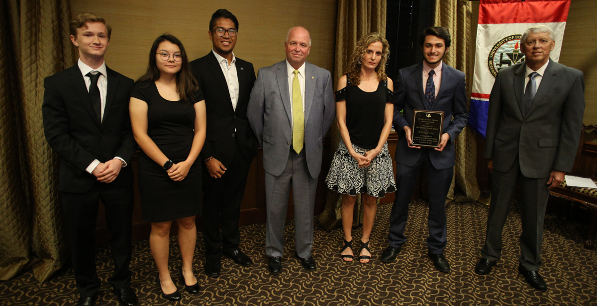 Stephen Azar, second from right, is the University of South Alabama Board of Trustees Scholar for the 2019-2020 academic year. Azar is a freshman from St. Patrick High School in Biloxi, Miss. The scholarship is awarded annually to the most academically talented student in each incoming freshman class at USA. Joining Azar at the USA Board of Trustees meeting are, from left, 2018 scholar Cody Dunlap of Mobile, 2017 recipient Ada Chaeli van der Zijp-Tan of Madison, Ala., 2016 recipient Christian Manganti of Gulfport, Miss., Board of Trustees chair pro tempore Jimmy Shumock; Rana Azar, Stephen Azar's mother; Azar, and University President Tony Waldrop. 
 data-lightbox='featured'