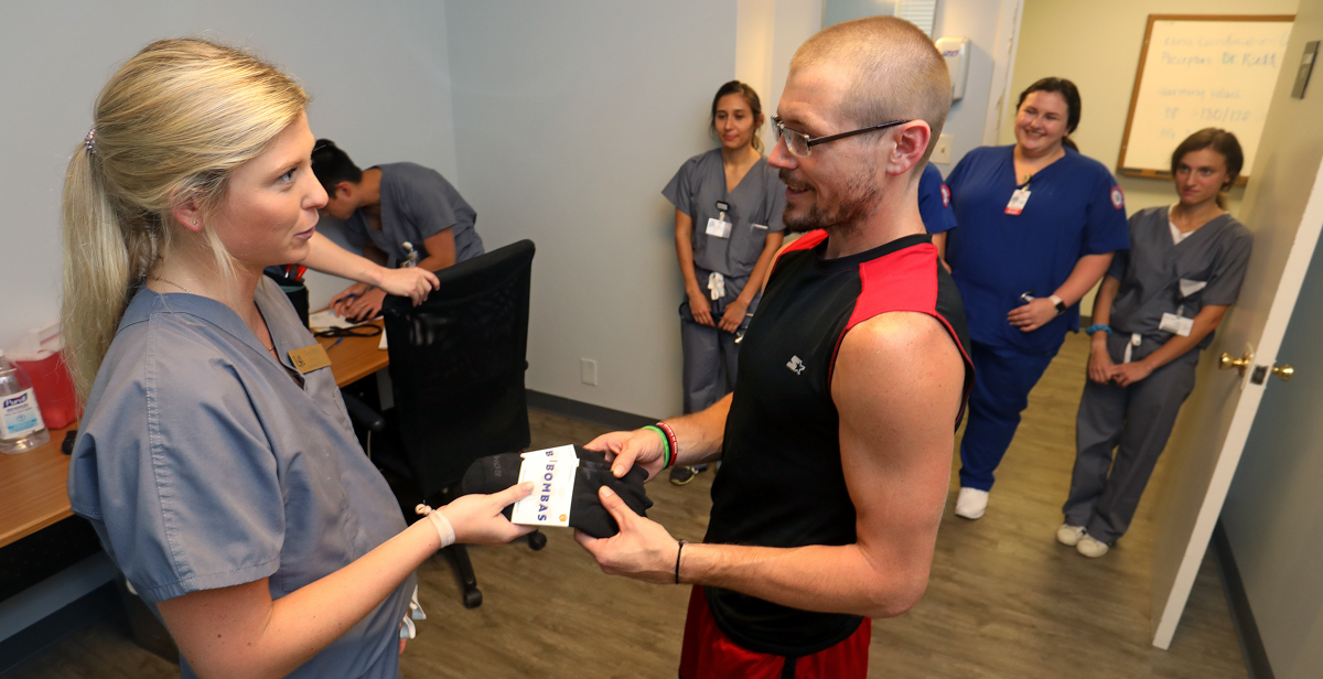 University of South Alabama College of Medicine medical student Corey Phillis gives a pair of socks to Paul Brown at the USA Student-Run Free Clinic. data-lightbox='featured'