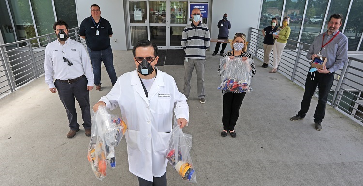 Dr. Benjamin Estrada, front, an infectious disease specialist at USA Health, accepted a delivery Friday of medical masks and tension-relief bands made by Airbus engineers and faculty at the University of South Alabama.