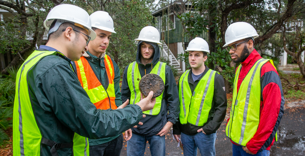 University of South Alabama engineering students examine an asphalt pavement core sample held by Dr. Shenghua Wu, assistant professor of civil engineering/pavement engineering. The sample was removed from a road made from 100 percent reclaimed asphalt pavement, which is the focus of research by Wu and the students.