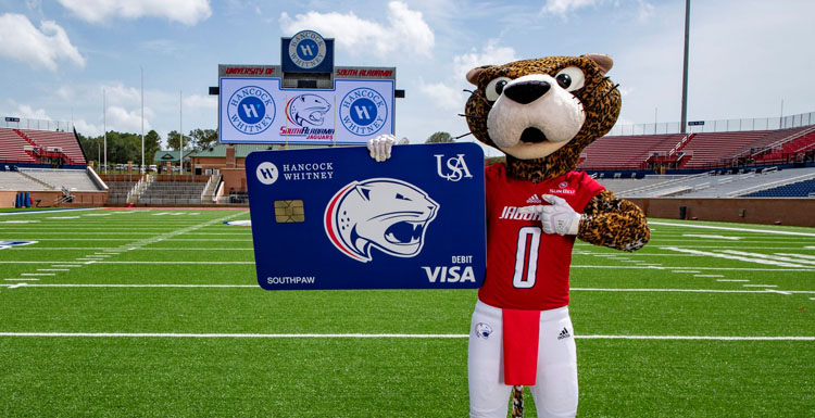 USA mascot SouthPaw shows off the new Hancock Whitney Jaguars branded debit card.