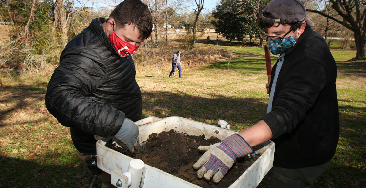 From L-R; Will Marriott, staff archaeologist, USA Center for Archaeological Studies, and Jeremy Pruitt, field technician, USA Center for Archaeological Studies sift through soil collected during a cultural resource survey in the Africatown community of Mobile.