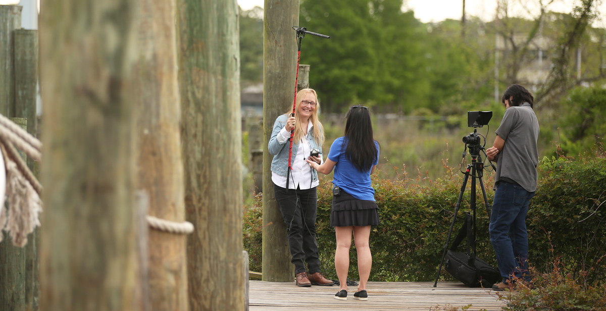 Dr. Lorraine Ahearn, an assistant professor of multimedia journalism at the University of South Alabama, holds a boom microphone for her interview with a Bayou Le Batre resident who moved there from Vietnam as a child. Ahearn is producing a documentary about the Vietnamese fishing community on the Alabama Gulf Coast. The videographer on many of her interviews is Francisco Cordova, right, a December graduate from the digital cinema and television program.
