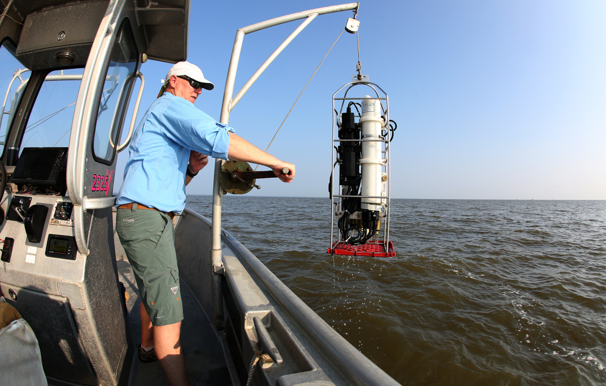 Dr. John Lehrter, associate professor of marine science, pulls up a submersible instrument used to measure the water's temperature and oxygen and salinity levels.