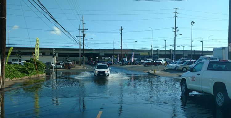 Saltwater flooding in a busy intersection in Oahu, HI is the result of sea level rise causing higher tides that back up the stormwater system. This type of flooding is known as "high tide flooding," "sunny day flooding," or "nuisance flooding." It's an example of how sea-level rise is affecting everyday life in coastal regions.