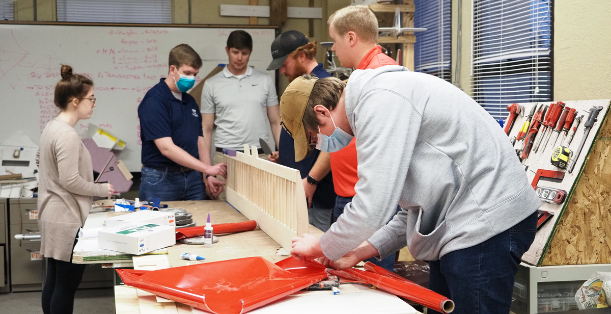 University of South Alabama mechanical engineering seniors, from left, Madison Bomeke, Hayden Jenkins, Bryson Hatcher, Will Sergeant, Gavin Brown and Evan Moulds work on a 82-inch-long wing that will provide stability for their remote-control cargo plane in the Design, Build, Fly competition.  data-lightbox='featured'