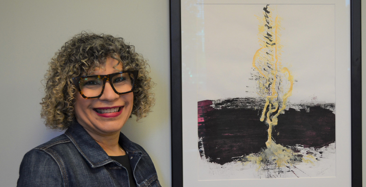 Alma Hoffmann, an associate professor of graphic design, poses with her painting 'Micah 4' which was named by Creative Quarterly as one of the 100 Best Artworks of 2021.  data-lightbox='featured'