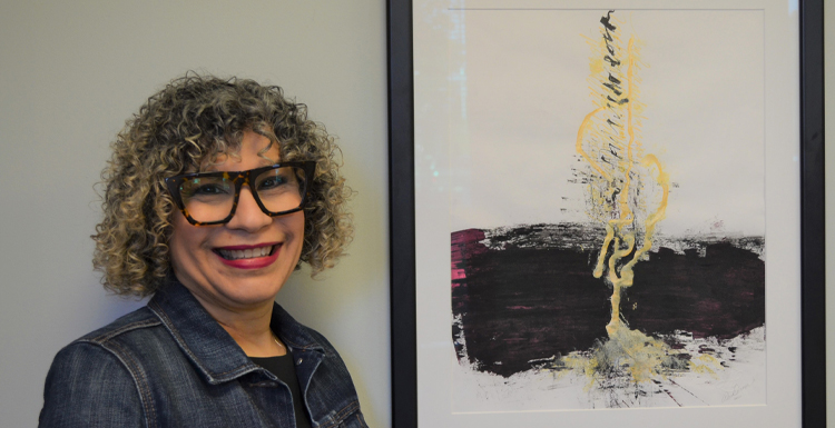 Alma Hoffmann, an associate professor of graphic design, poses with her painting 'Micah 4' which was named by Creative Quarterly as one of the 100 Best Artworks of 2021. data-lightbox='featured'