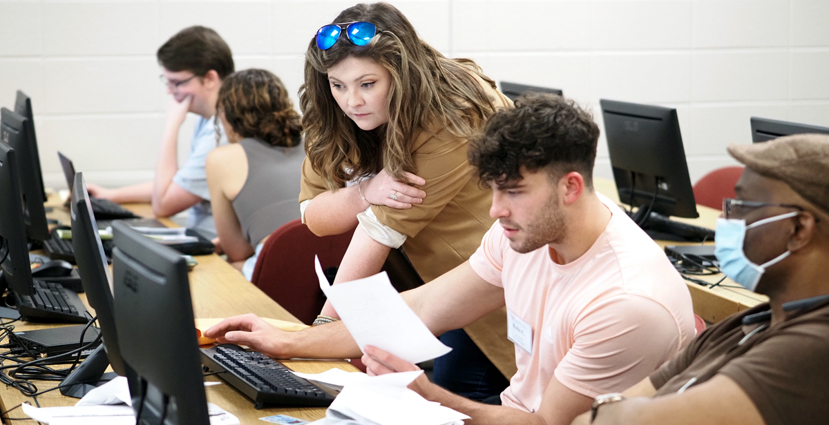 Margaret Bradford, site coordinator for the VITA program at the University of South Alabama, helps Kobe Cox, an accounting major and student volunteer, fill out a tax return for a Mobile resident.