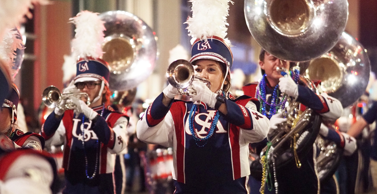 The Jaguar Marching Band leads the way for the Infant Mystics on Monday in downtown Mobile.