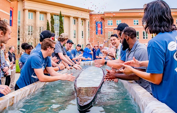 University of South Alabama College of Engineering students test the buoyancy of their 250-pound concrete canoe outside Shelby Hall. The group placed third in the competition on Dog River.  