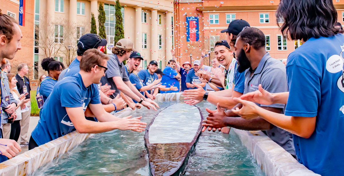 University of South Alabama College of Engineering students test the buoyancy of their 250-pound concrete canoe outside Shelby Hall. The group placed third in the competition on Dog River.  