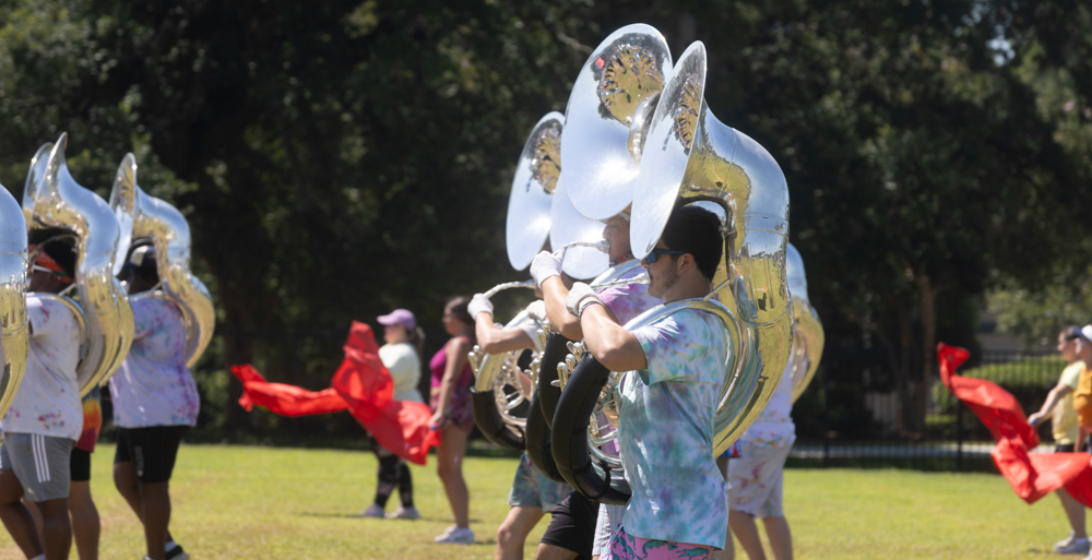 Sousaphone players and the color guard march across the Jaguar Marching Band practice field on the last full day of Band Camp.