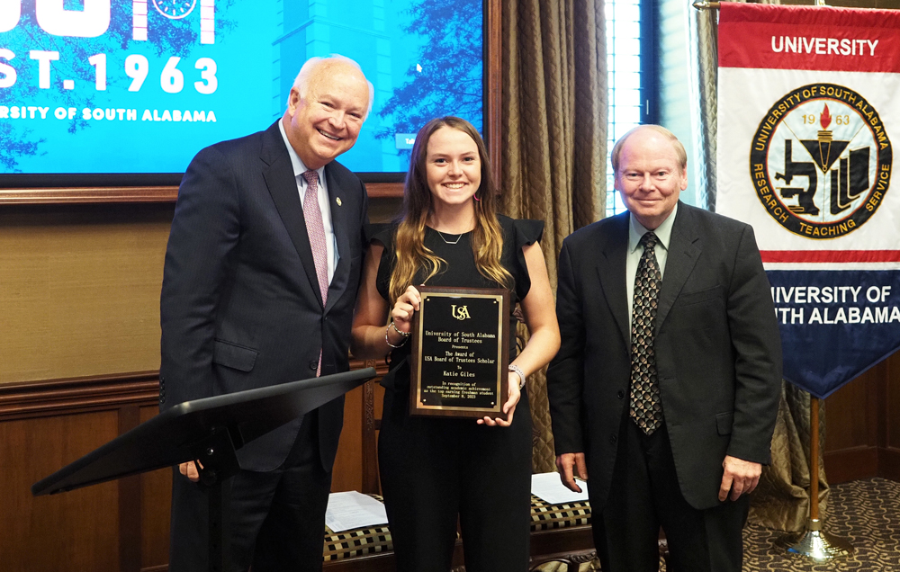 Katie Giles, center, was recognized at the September Board of Trustees quarterly meeting as the 2023-24 Board of Trustees Scholar. President Jo Bonner, left, and Trustee Dr. Steve Furr, who led the creation of the scholarship in 2014, presented her with a plaque.