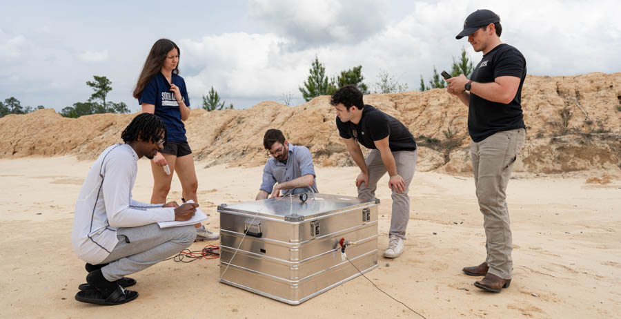 University of South Alabama students, from left, Devon Edinburgh, Paige Palazzo, Matthew Crump, Reed Turner and Luke Andress run though a series of tests on their senior research project at a firing range north of Mobile. 