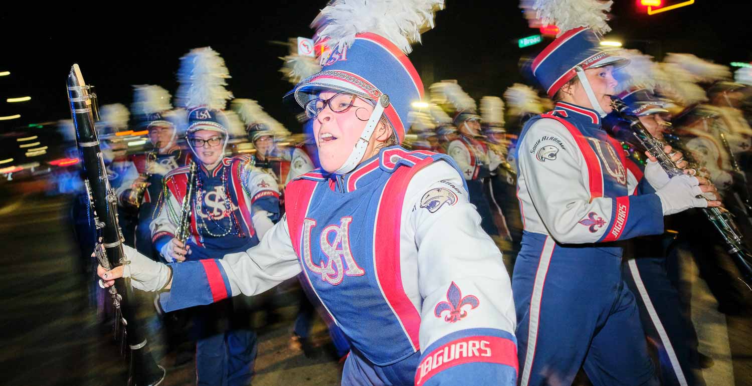 Jaguar marching band parading with the Mystic Stripers