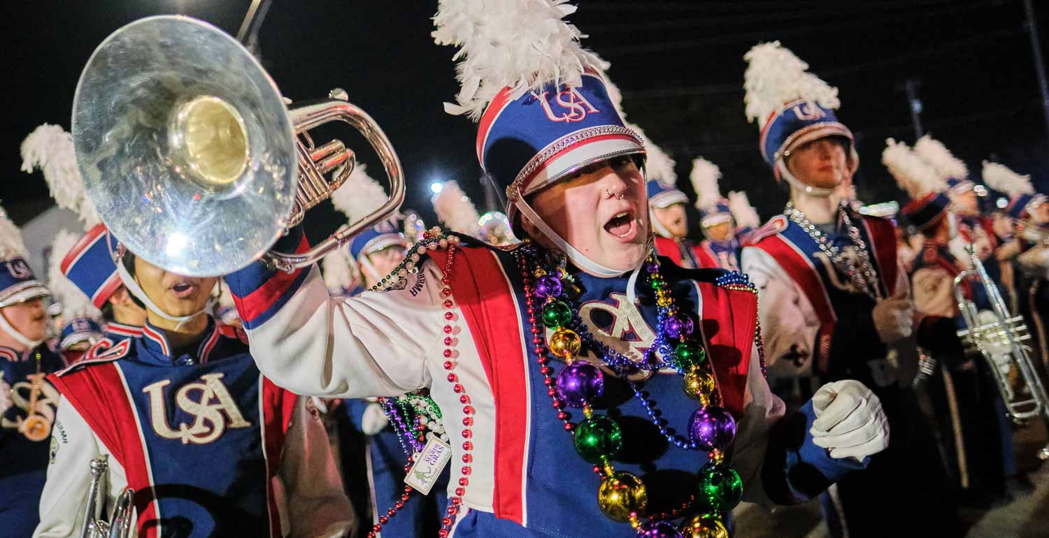 Jaguar marching band parading with the Mystic Stripers