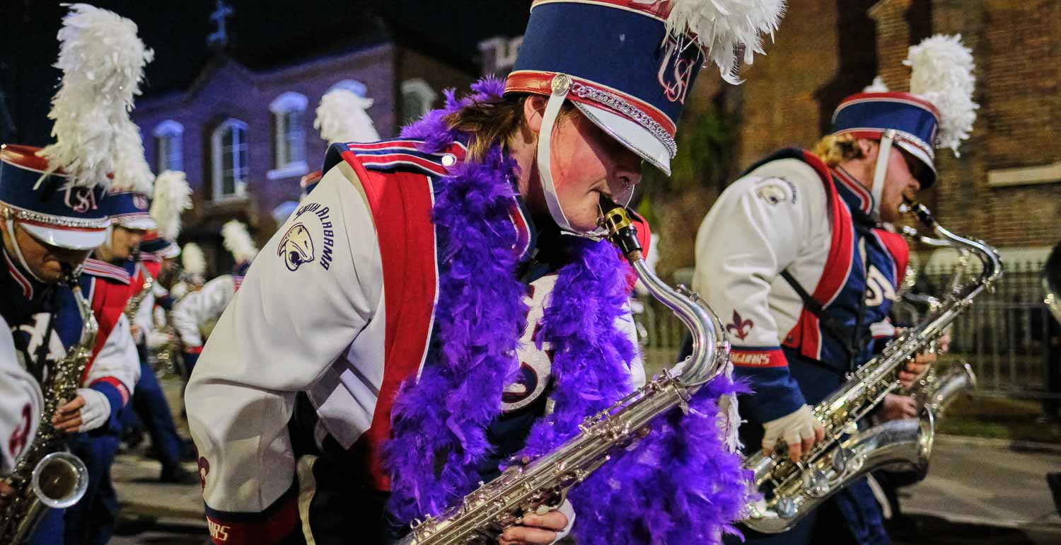 Jaguar marching band parading with the Mystic Stripers