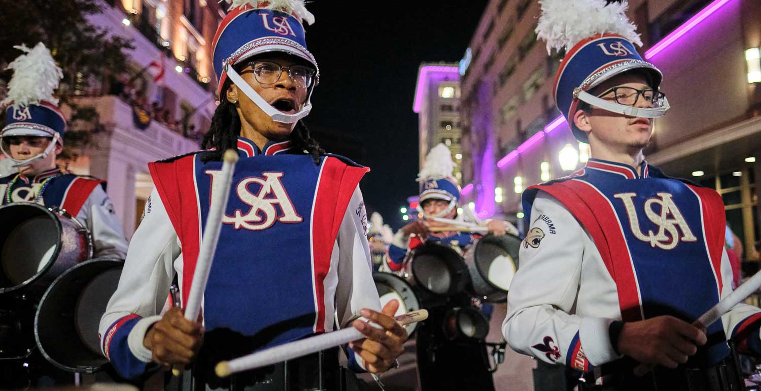 Jaguar marching band parading with the Mystic Stripers