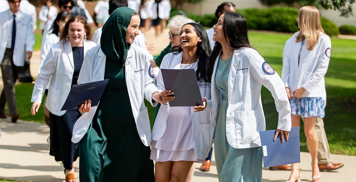 Three Gold Humanism Honor Society Inductees walking outside. 