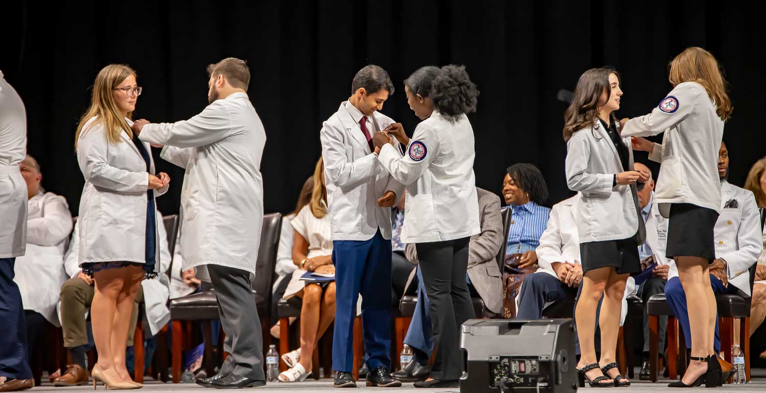 Gold Humanism Honor Society Inductees pinning each other on stage.