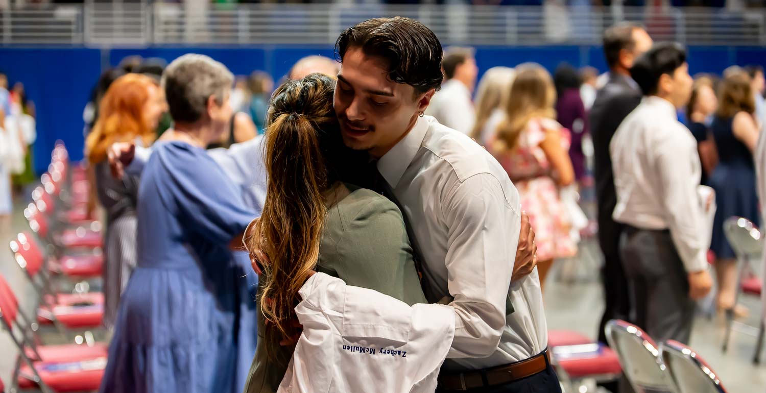 Medical Student hugging family member at Class of 2028 White Coat Ceremony.