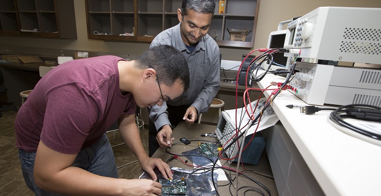 Brannon Kerrigan and Dr. Edmund Spencer examine a TDIP instrument they developed in the College of Engineering.  An identical TDIP was launched in a NASA rocket on March 1.  