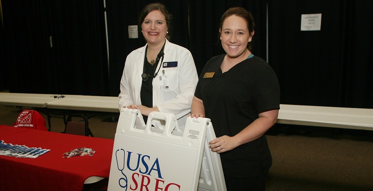 Dr. Alison Rudd, assistant director of the Human Simulation Program and faculty advisor for the Student-Run Free Clinic and Morgan Watkins, a social work major in the College of Arts and Sciences provide health and wellness information at the Mobile Project Homeless Connect held on Jan. 28, at the Mobile Greater Gulf State Fair Grounds.