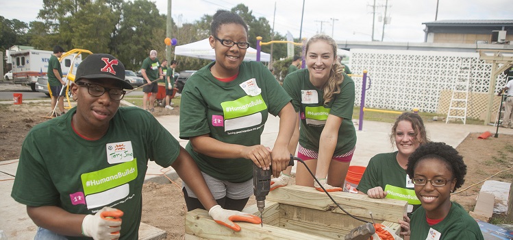 five service volunteers wearing green Humana Builds t-shirts on building site