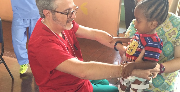 Dr. Dennis Fell, USA chair of physical therapy, helps Kadeon stand with assistance from Jennifer Melancon, a USA physical therapy graduate, during a medical mission trip to Trinidad.