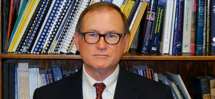 Dr. Michael Daley standing in front of bookcase filled with books