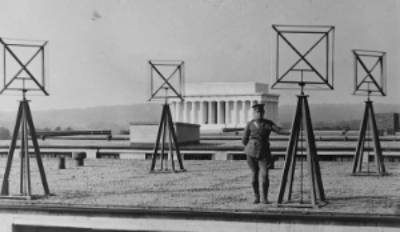 Image of a soldier standing next to radio antenna/satellite radars