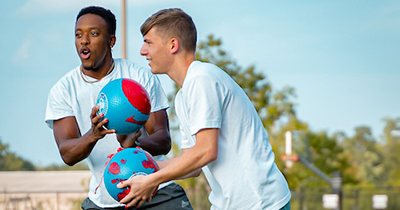 Two students playing sports on campus.